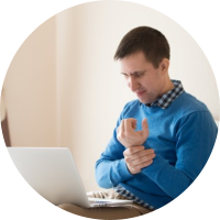 Image of man holding his injuted wrist and checking his computer for insurance information